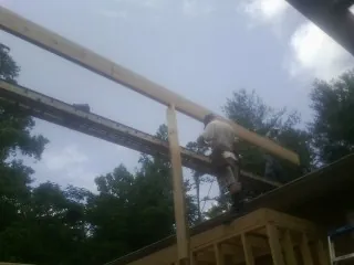 Carpenter setting a ridge beam over a new addition frame — Ice Dam Removal by Roofing Brothers in Havensville
