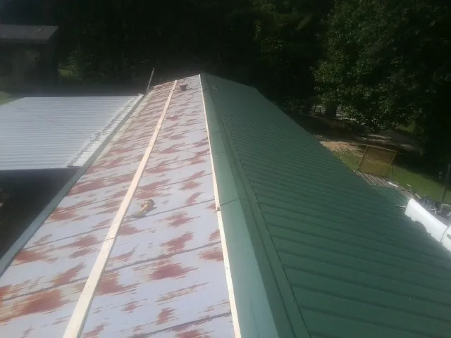Old rusted panels beside newly installed green metal roofing — Wind Damage Roof Repair by Roofing Brothers in Havensville