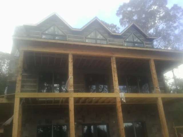 Dormers and porch framing on a large log home under construction — Roof Coating work by our crew in Havensville