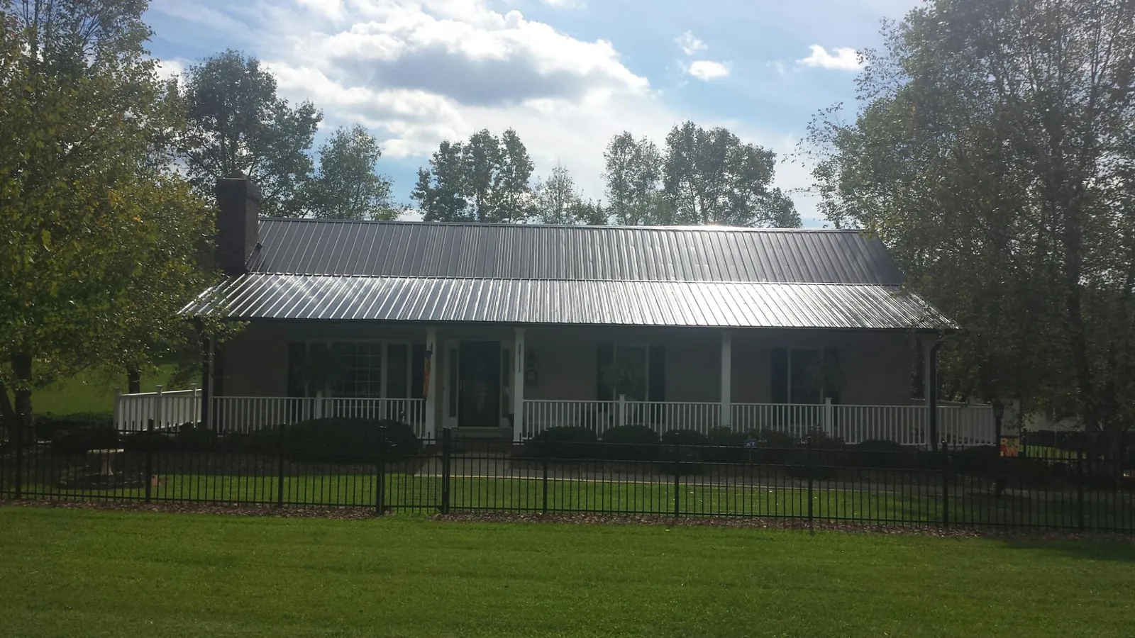 Gray metal roof on a brick ranch with a full width front porch — Gutter Guard Installation work by our crew in Havensville