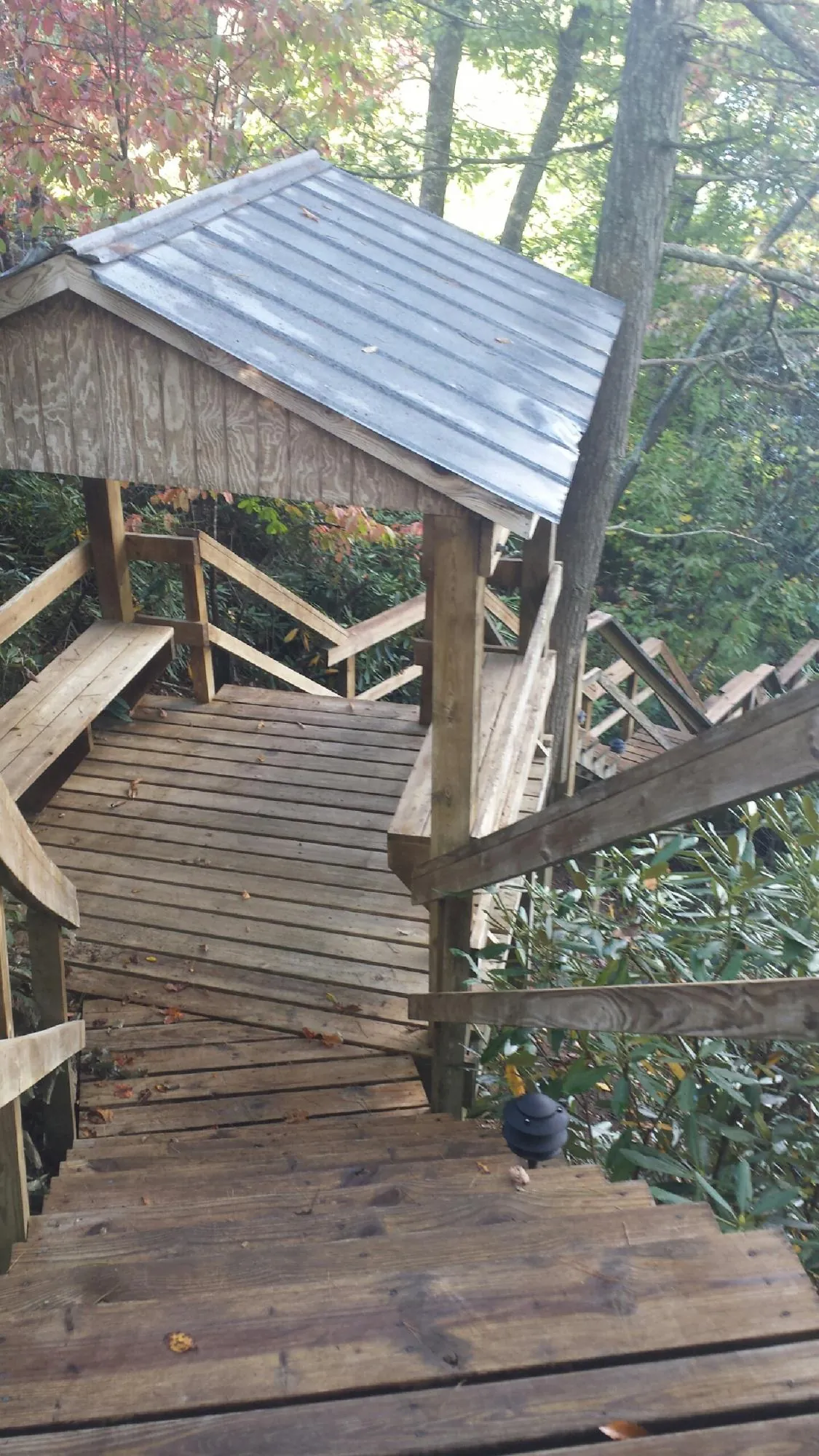 Metal roofed shelter over wooden steps on a wooded walkway — Skylight Repair & Installation work by our crew in Havensville