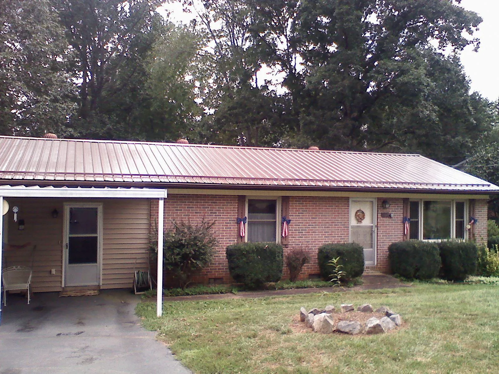 Bronze metal roof and carport on a brick ranch home — Roof Repair work by our crew in Havensville