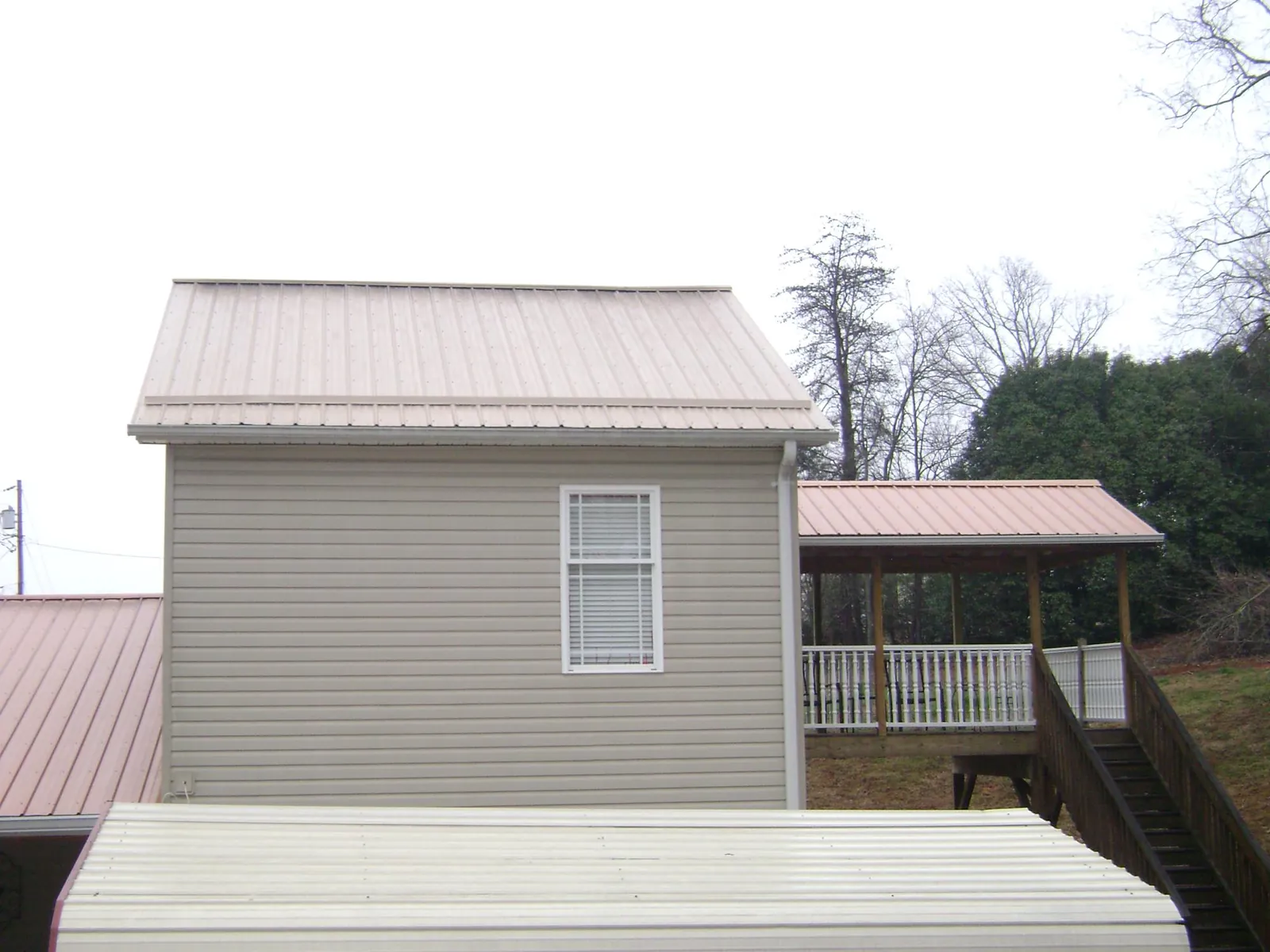 Tan metal roofs on a two story addition and attached porch, from a Roof Replacement job in Havensville