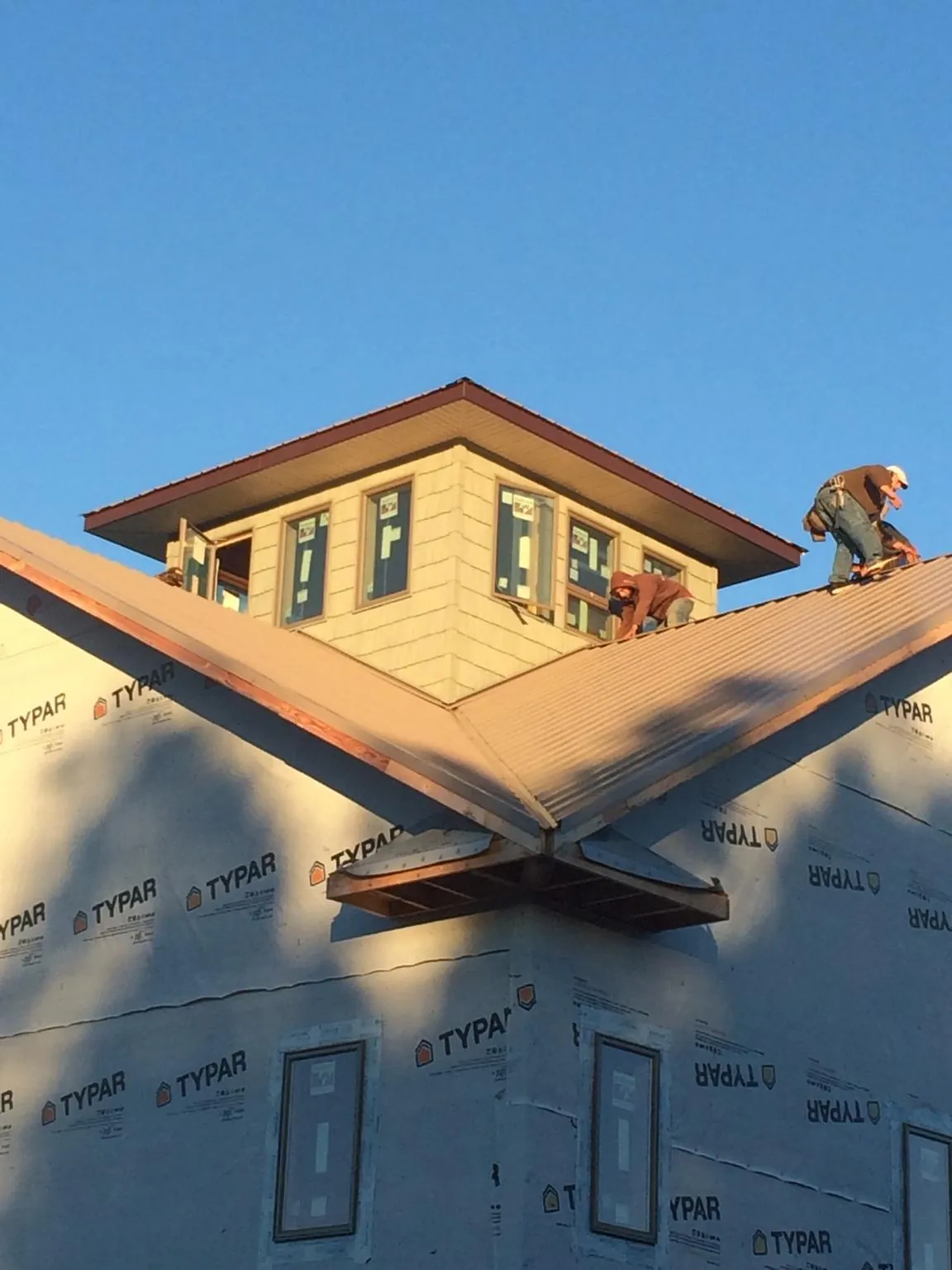 Roofers working around a rooftop cupola on a new metal roof at sunset — Roof Waterproofing in Havensville by Roofing Brothers